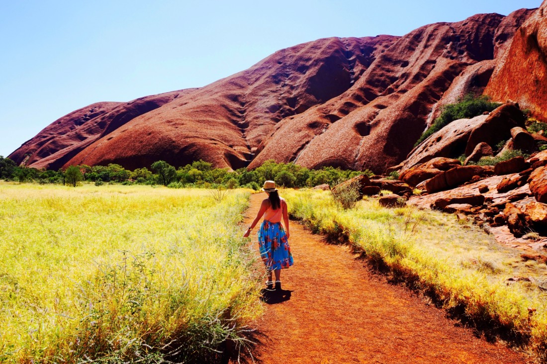 Girl in floral skirt walks towards Uluru